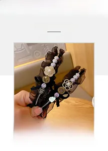 Detail of black lace headband with pearls, rhinestones and camellia floral decor