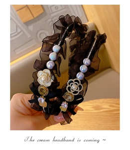 Detailed close-up of a black mesh headband featuring camellia flowers and sparkling rhinestones