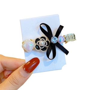 Camellia flower and bow hair clip with pearls and rhinestones on a display card