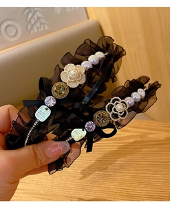 Detail of vintage camellia headband featuring black lace, pearls, and a metal tag