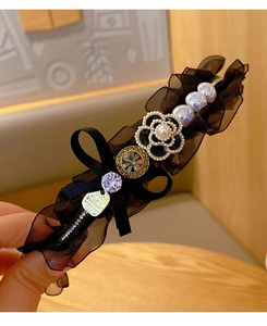 Detail of camellia hair clip with black velvet bow, white pearls, and rhinestone accents