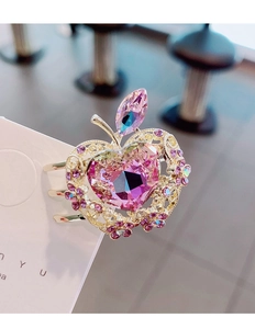 Detalle de pinza de pelo de manzana con gema rosa de corazón y borde de encaje dorado