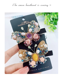 Détail de deux barrettes papillon faites à la main avec perles et pierres violettes
