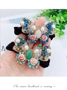 Détail de l'élastique à cheveux papillon baroque avec perles, pierres et roses en résine