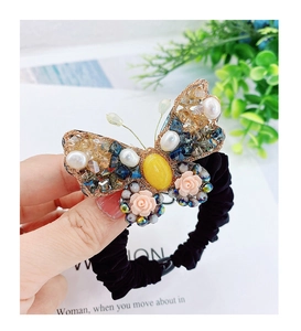 Vue détaillée d'un élastique papillon avec fil doré, perles et pierres colorées