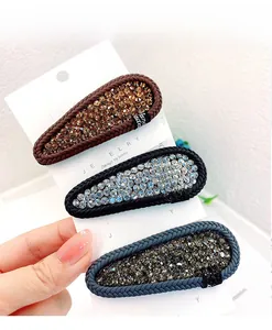 Detail of three handmade drop-shaped hair clips with rhinestones and woven edges