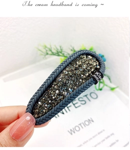 Close-up of handmade gray rhinestone BB clip with braided edges and a handmade label