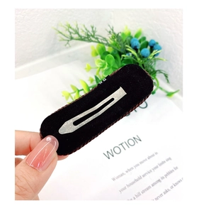 Detail of a dark flocked BB hair clip with woven edges and silver metal base