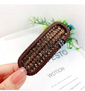 Detail of brown braided hair clip with amber crystals and Hand Made woven label