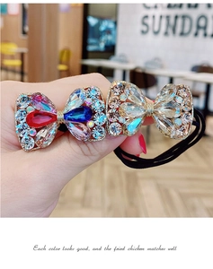 Vue détaillée d'un élastique à cheveux noir orné de double nœuds avec des strass multicolores