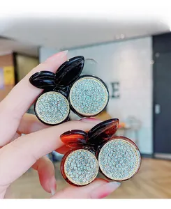 Detailed view of cherry-shaped hair claws featuring sparkling rhinestones in black and amber