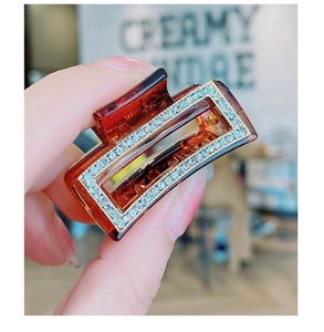 Detailed macro view of amber resin hair claw clip with blue and white rhinestones