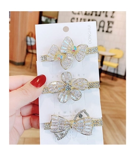 Drei goldene Haarspangen mit Schmetterlings- und Blumenmotiven sowie funkelnden Kristallen
