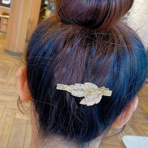 Eleganter goldener Haarclip in Blattform mit Strasssteinen an einem Haarknoten