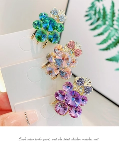 Detailed view of floral crystal hair clips in green, pink and purple with rhinestone bows