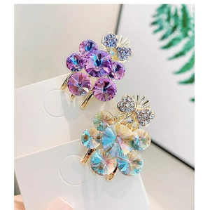 Macro view of crystal flower hair clips with golden metal base and butterfly detail