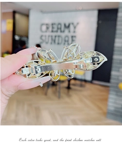 Détail du mécanisme de la pince croco sur une barrette papillon dorée avec cristaux