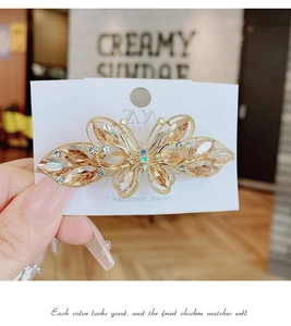 Gros plan d'une pince à cheveux papillon dorée avec des cristaux de couleur champagne