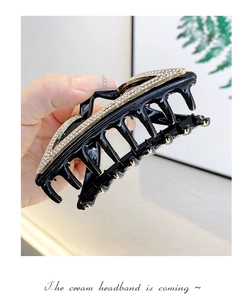 Macro shot of stylish black hair claw clip decorated with sparkling crystal rhinestones