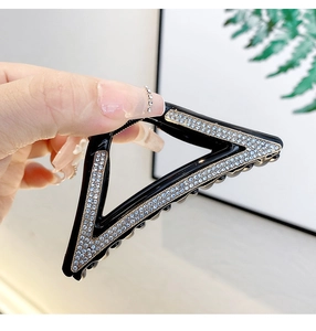 Macro detail of a large black triangle shark clip with glittering white rhinestones
