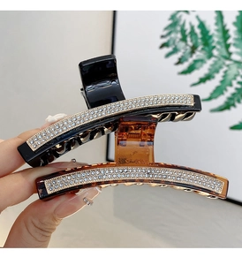 Detail of luxury hair claws with three rows of sparkling rhinestones in black and amber