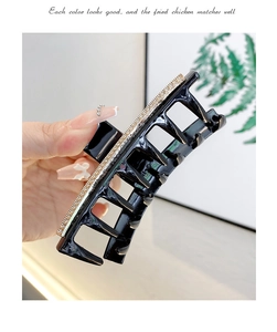 Close-up detail of a black large hair claw clip decorated with shiny white rhinestones