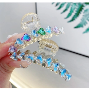 Dettaglio di un fermaglio per capelli in acrilico con strass colorati a forma di cuore e luce
