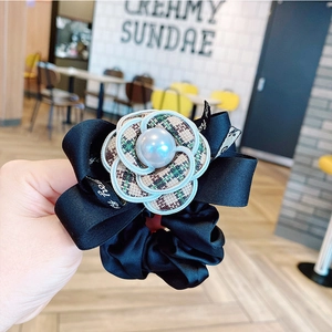 Elegant camellia hair scrunchie with plaid patterns, pearl center, and black ribbon bow