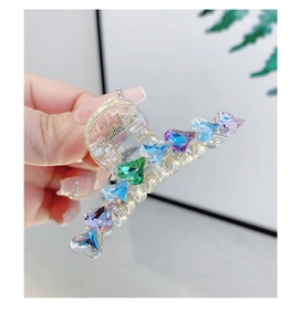 Dettaglio della molletta per capelli in acrilico trasparente con strass colorati a cuore e molla