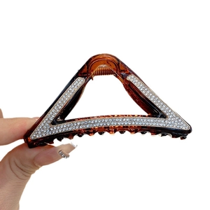 Amber resin triangle hair claw clip with rhinestones shown in a hand-held display
