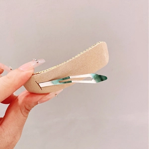 Detailed back view of a beige fabric snap clip showing the sturdy silver metal spring mechanism