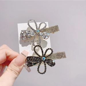 Detailed view of floral rhinestone hair clips in white and grey with golden alloy base