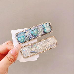 Sparkly heart hair clips with pearls and rhinestones on a white display card