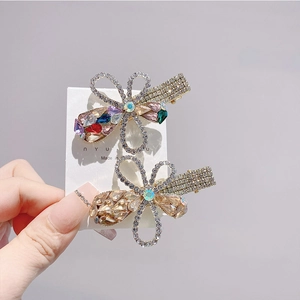 Detail of floral and bow hair clips with champagne rhinestones on a card holder
