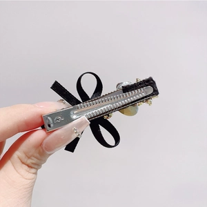 Detail of black satin bow hair clip with sparkling crystal beads and metal duckbill clip