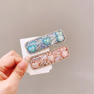 Detail of light blue and pink heart hair clips with pearls and rhinestones on card