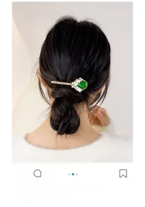 Detail view of emerald stone hair clip with flower pearl decor on dark hair
