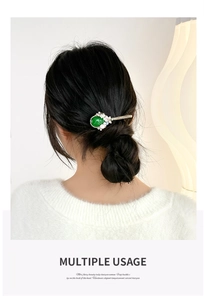 Detailed view of an emerald cat-eye stone hair clip with pearls on a low bun hairstyle