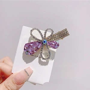 Detailed close-up of a purple crystal butterfly hair clip with sparkling silver rhinestones