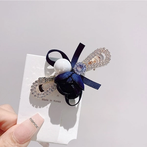 Détail d'une pince à cheveux rose en velours bleu marine avec perle et ruban de strass