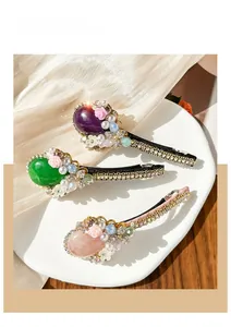 Detailed view of luxury duckbill hair clips with faux emeralds, pearls and rhinestones