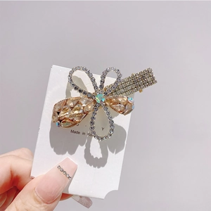 Detailed close-up of champagne crystal bow hair clip with fine rhinestone inlay