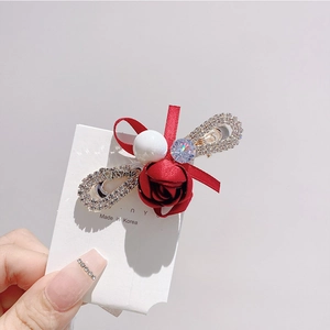 Détail d'une pince à cheveux rose rouge avec des perles blanches et des strass étincelants