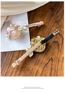 Détail d'une pince à cheveux avec roses roses, perles blanches et cristaux sur bois sombre