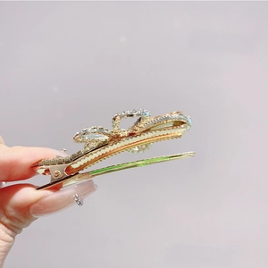 Detail of a gold-tone bow hair clip featuring sparkling rhinestones for hair styling