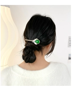 Baroque hair clip featuring emerald stones and pearls worn on dark hair
