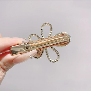 Close-up of golden floral hair clip with intricate hollow patterns and sparkling crystals