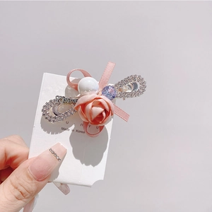 Détail d'une pince à cheveux avec rose en soie rose, perle blanche et symbole infini