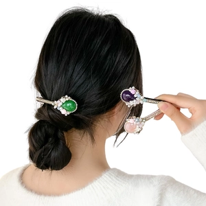Baroque hair clips with emerald cat-eye stones, pearls, and crystals on a hair bun