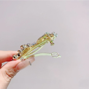 Detailed view of golden alloy hair clip with colorful rhinestones held by hand